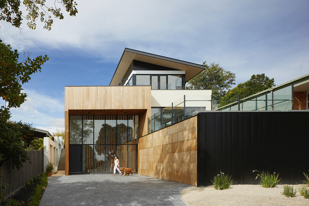 view of house from outside with square architecture, mostly made of wood panels and large glass windows